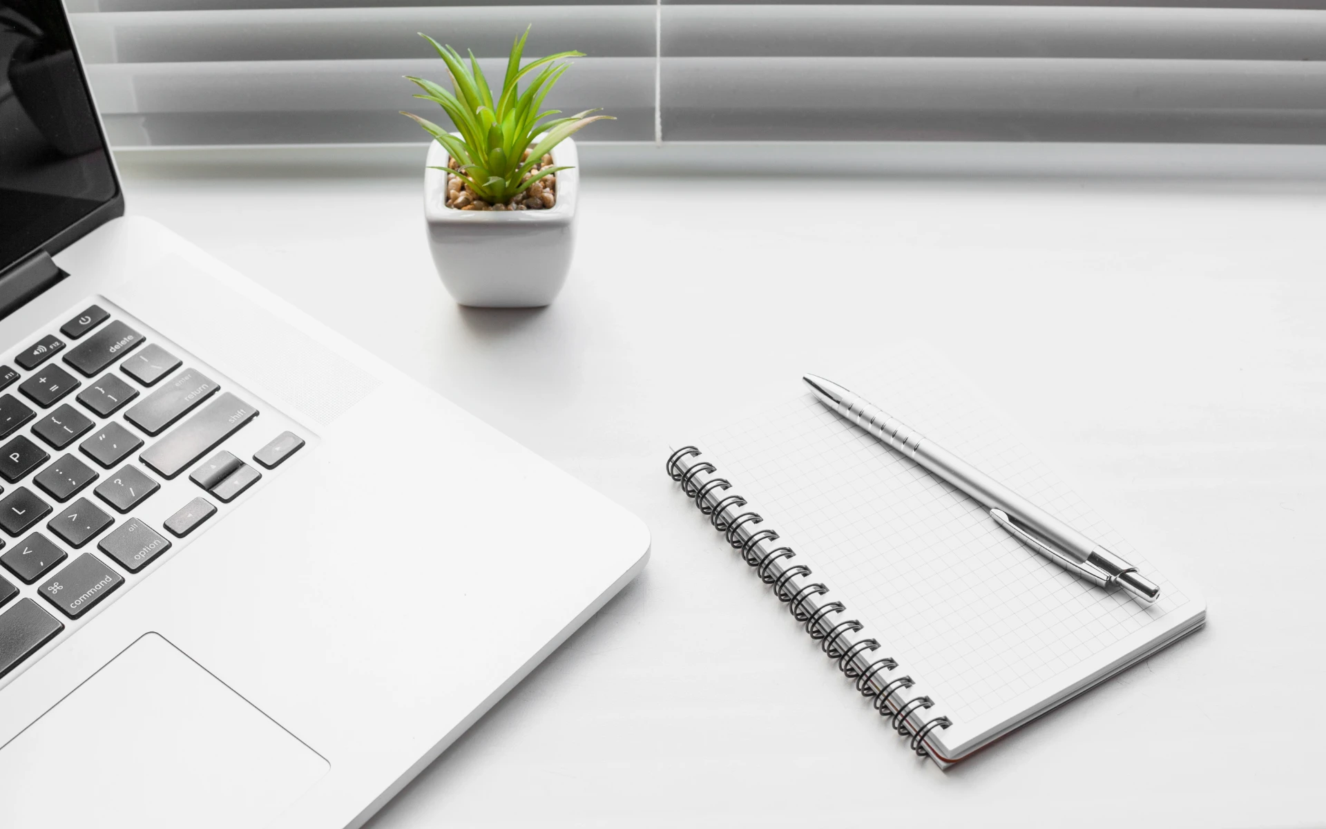 Laptop met notitieblok en pen op een bureau