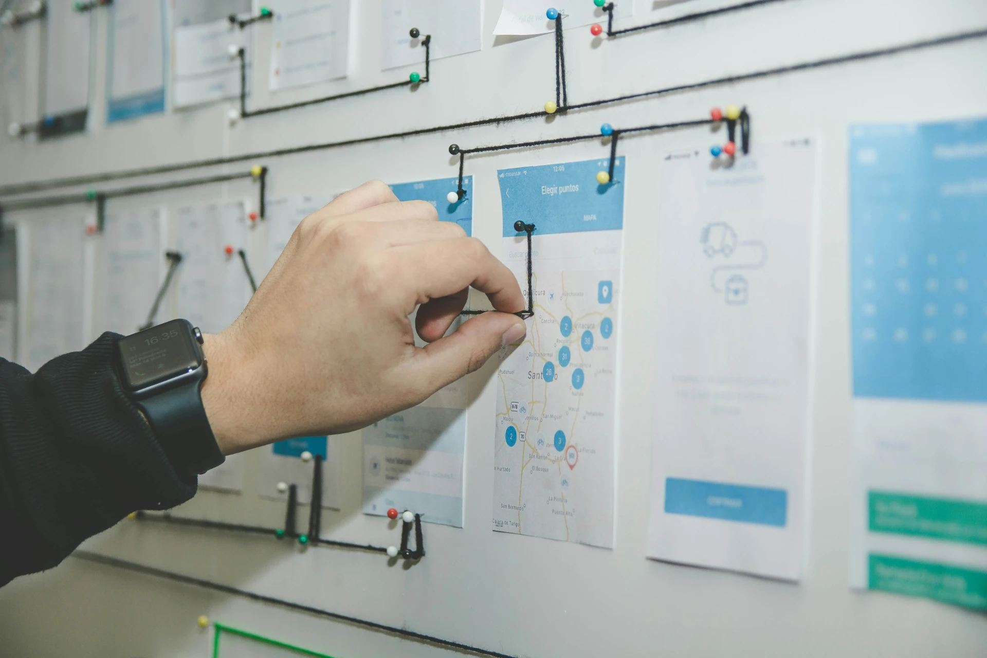 Hand die een mobiel wireframe uitwerkt op een planbord vol schetsen